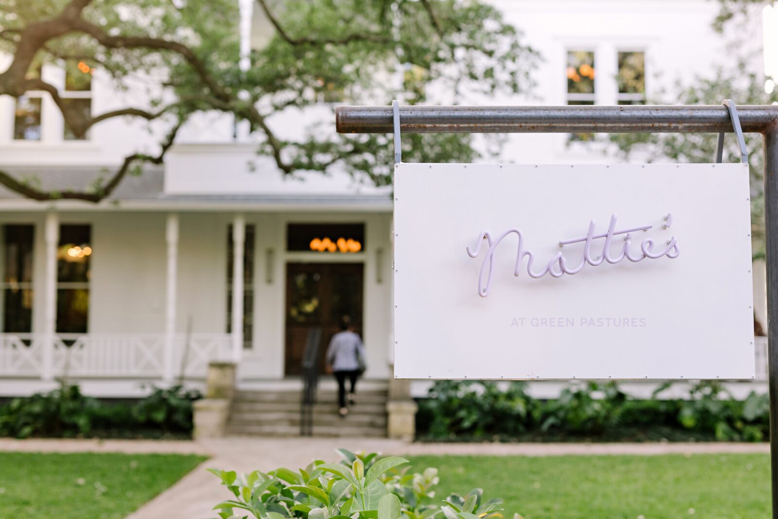 Sign for Mattie's at Green Pastures with historic building in background