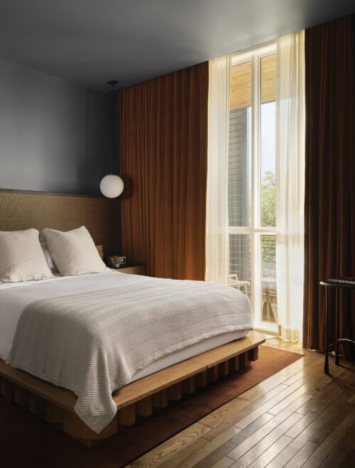 Modern bedroom with wooden bed natural light and brown curtains