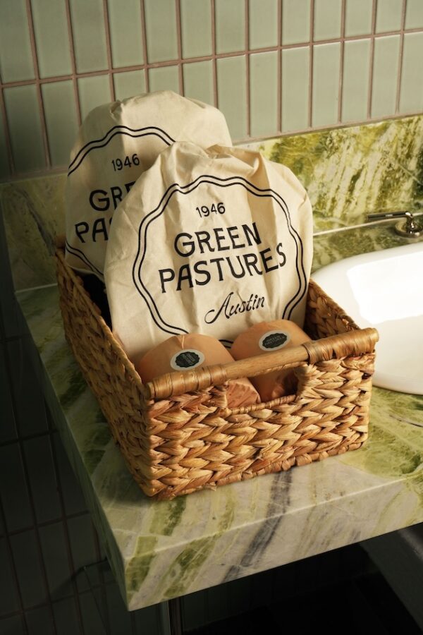 Wicker basket with Green Pastures branded bags and soaps on a stone countertop