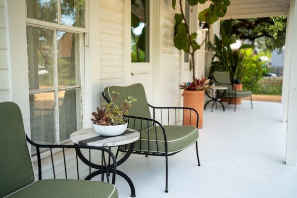 Charming porch with green chairs and potted plants for a relaxing outdoor space