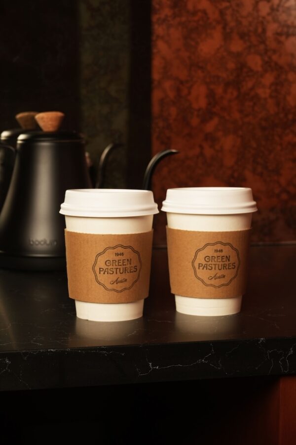 Two coffee cups with sleeves on a black counter in a cozy cafe setting