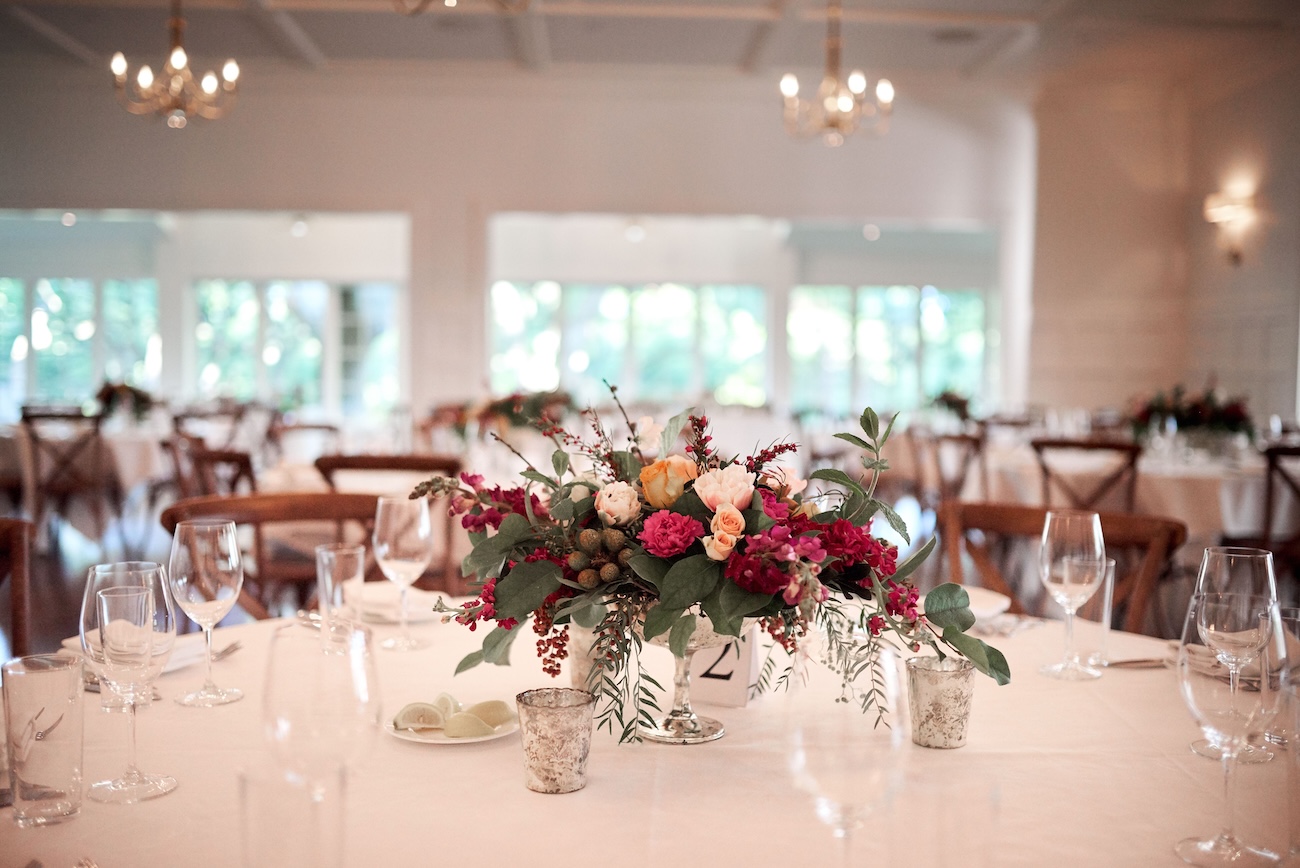 Elegant wedding reception table with floral centerpiece and glasses in a bright dining room