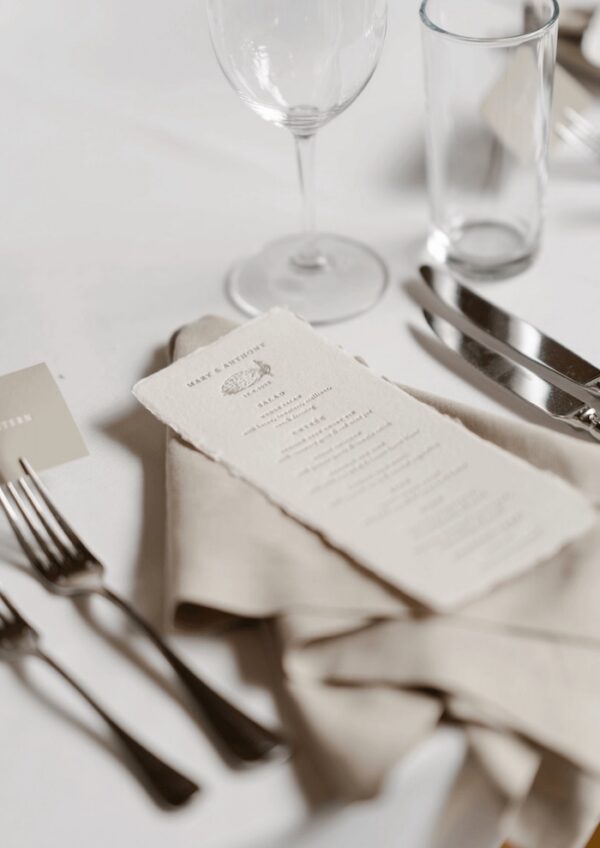 Elegant table setting with menu card and glassware on white tablecloth
