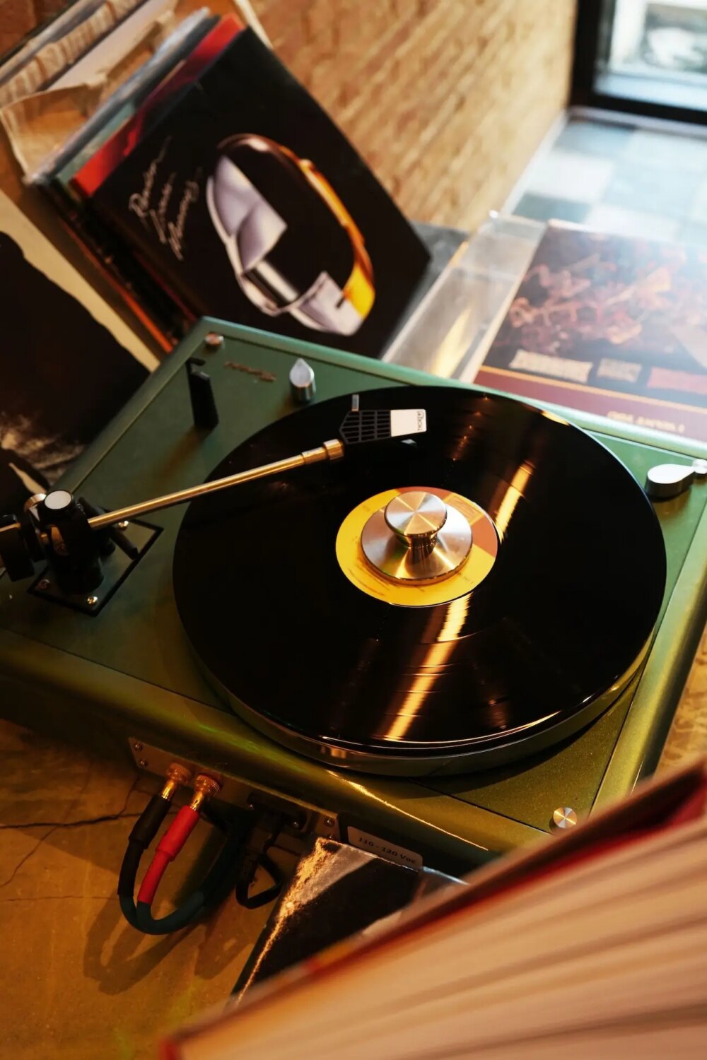 Vintage turntable playing a vinyl record with album covers in the background