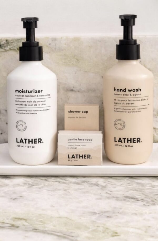 Lather skincare set with moisturizer hand wash face soap and shower cap on marble surface