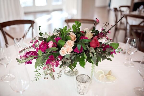 Elegant floral centerpiece with pink and peach roses on a wedding table setup.