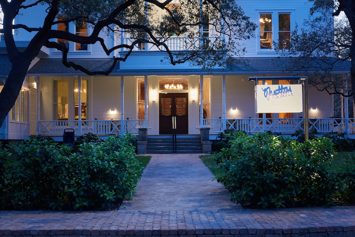 Charming restaurant exterior with warm lighting and lush greenery at dusk