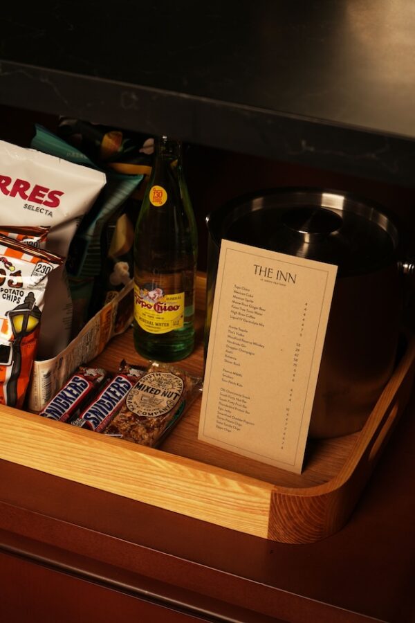 Hotel room snack tray with chips, bottled water, and menu on a wooden tray.
