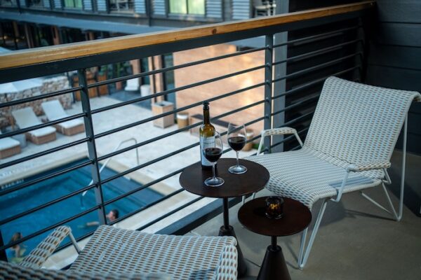Two chairs and a table with wine overlooking a pool from a balcony