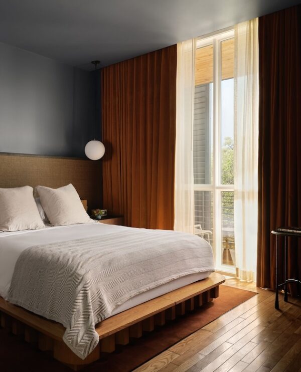 Modern bedroom with wooden floors neutral bedding large window and warm curtains