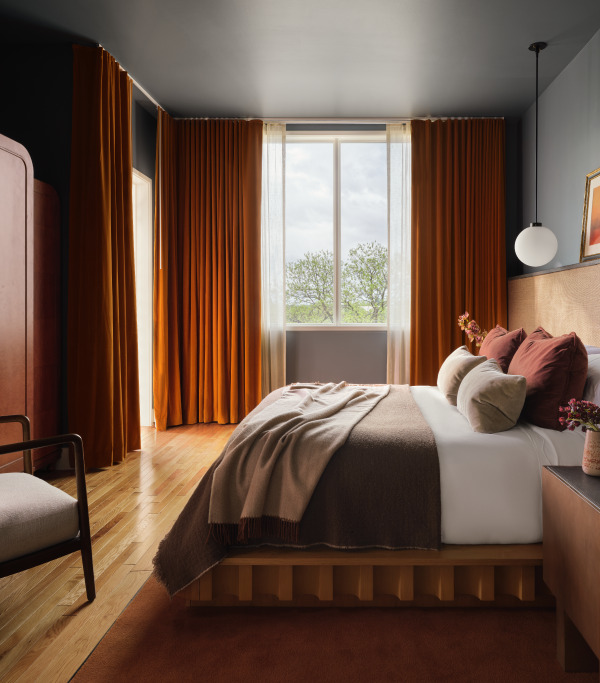 Cozy bedroom with orange curtains a large bed with brown bedding and a view through the window