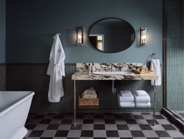 Elegant bathroom with marble sink vanity, oval mirror, bathrobe, and checkered floor tiles