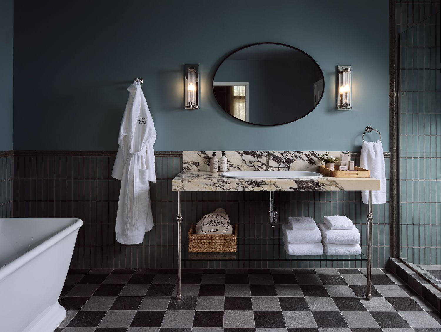 Elegant bathroom with marble sink vanity, oval mirror, bathrobe, and checkered floor tiles