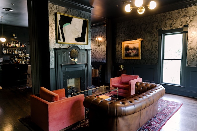 Stylish lounge with velvet chairs leather sofa a fireplace and bar area in cozy dim lighting