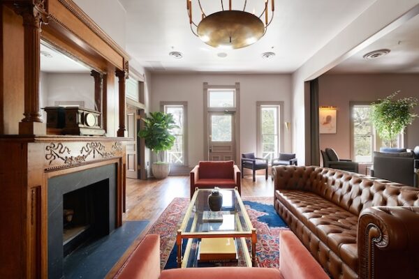 Elegant living room with leather sofa, armchairs, fireplace, and large windows offering natural light