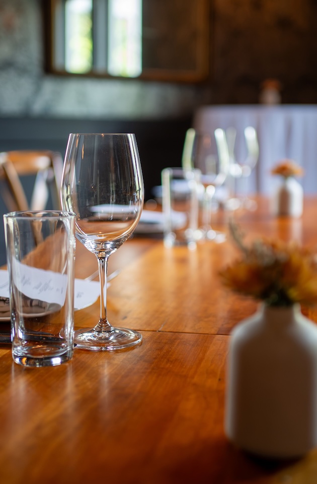 Elegant table setting with wine glasses and flowers on a wooden surface in a cozy restaurant ambiance.