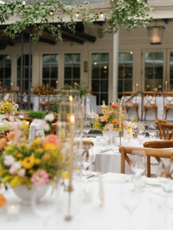 Elegant outdoor wedding reception setup with floral centerpieces and hanging greenery